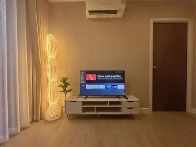 a television sitting on a stand in a living room at Metro luxe riverfront resort style condo in Ban Sai Ma