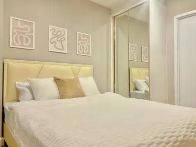 a bedroom with a white bed and a mirror at Metro luxe riverfront resort style condo in Ban Sai Ma