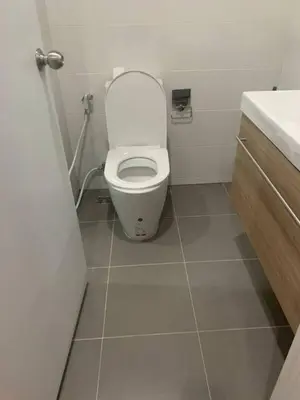 a small bathroom with a toilet and a sink at Metro luxe riverfront resort style condo in Ban Sai Ma