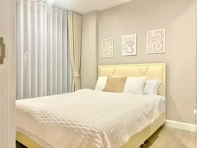 a bedroom with a white bed and a window at Metro luxe riverfront resort style condo in Ban Sai Ma