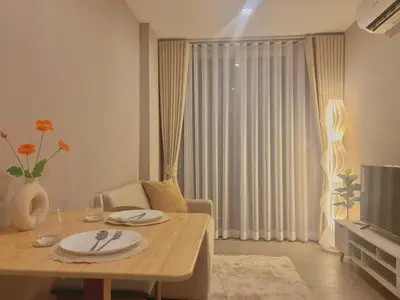 a living room with a table and a television at Metro luxe riverfront resort style condo in Ban Sai Ma