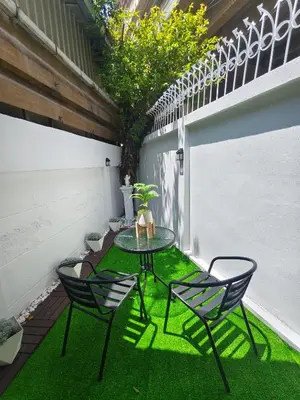 a patio with a table and chairs on the grass at Charming 3-Storey house near BTS Onnut Station in Bangkok