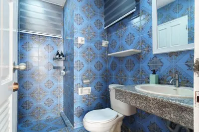 a blue tiled bathroom with a toilet and a sink at Charming 3-Storey house near BTS Onnut Station in Bangkok