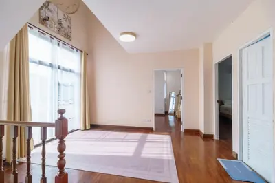 a living room with a staircase and a large window at Charming 3-Storey house near BTS Onnut Station in Bangkok