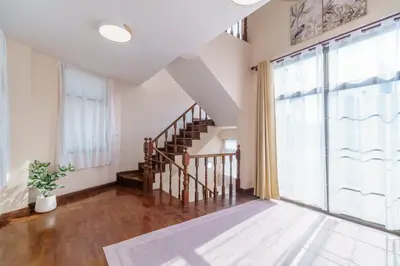 a living room with a staircase and a large window at Charming 3-Storey house near BTS Onnut Station in Bangkok