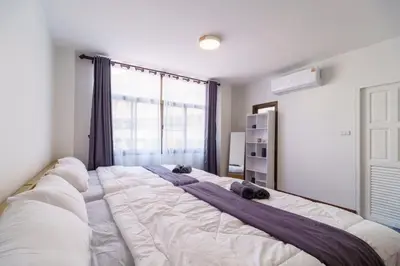 a large white bed in a room with a window at Charming 3-Storey house near BTS Onnut Station in Bangkok