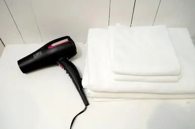 a black hair dryer sitting next to a white towel at Designer house Chao Phraya River - OH Homes 12 in Bangkok