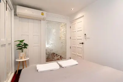 a white bedroom with a bed and a window at Designer house Chao Phraya River - OH Homes 12 in Bangkok