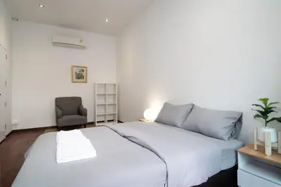 a bedroom with a large white bed and a chair at Designer house Chao Phraya River - OH Homes 12 in Bangkok