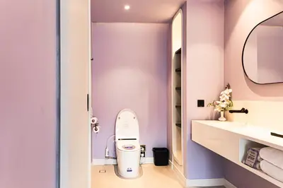 a bathroom with a toilet and a purple wall at Queensland Hotel Bangkok in Bangkok