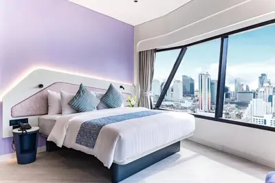a bedroom with a large bed and a large window at Queensland Hotel Bangkok in Bangkok