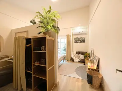 a living room with a plant on top of a book shelf at Enjoyo Getaway in Bangkok