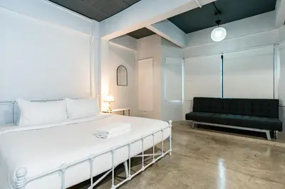 a bedroom with a white bed and a couch at xx Yellow Place Sukhumvit 2 - BTS Nana Pro in Bangkok