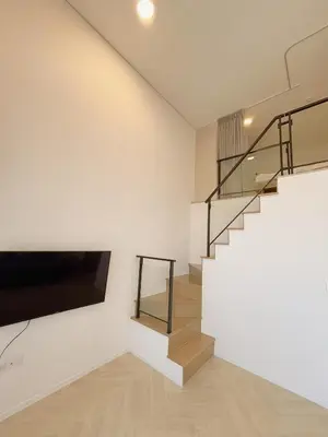 a living room with a staircase and a flat screen tv at Cassia Rama9 Loft Highrise View Central in Bangkok