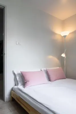a bedroom with a white bed with pink pillows at Baan Khun Pra No 1 Bangkok Duplex in Bangkok