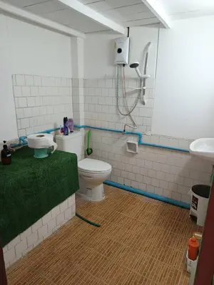 a bathroom with a toilet and a green rug at Sleep Break Hostel Sathon in Bangkok