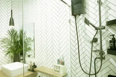 a bathroom with a white tiled wall at Enjoyo getaway in Ban Zong Katiam