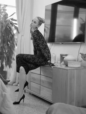 a woman sitting on a dresser in front of a tv at Siri Designer 3-Storey Townhouse with Garden and Luxury Amenities in Bangkok
