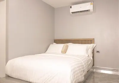 a bedroom with a white bed and a air conditioner at Cabanaz Pool Villa in Ban Zong Katiam