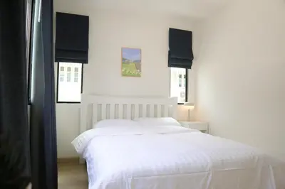 a white bed in a bedroom with two windows at Cozy Homey Place Townhome in Bangkok