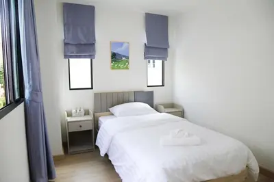 two beds in a bedroom with two windows at Cozy Homey Place Townhome in Bangkok