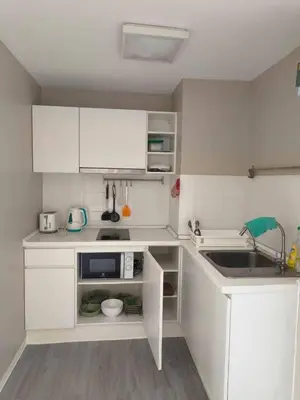 a small kitchen with white cabinets and a sink at Beautiful Studio Room Near MRT in Bangkok