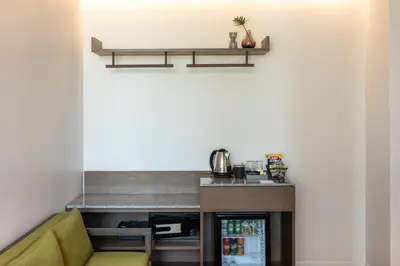 a kitchen with a counter and a yellow couch at Norma Hotel Sathorn in Bangkok