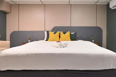 a large white bed with two towels on it at Floton Bangkok Hotel in Bangkok