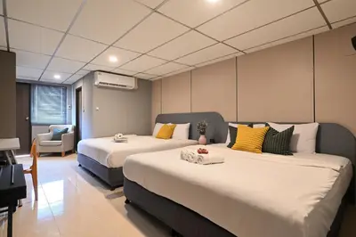 a hotel room with two beds and a chair at Floton Bangkok Hotel in Bangkok