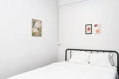 a bed with white sheets and two pictures on the wall at xx BAO The Giant Swing - Sao Chingcha - เบา ศาลเจ้าพ่อเสือ เสาชิงช้า in Bangkok
