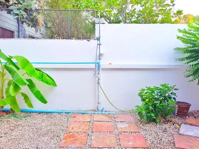 a garden hose hooked up to a white fence at Retreat House 81 - BTS Onnut in Bangkok