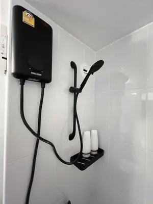 a bathroom with a shower with a hair dryer at Impact - Donmueng Popular C4 in Ban Song Hong