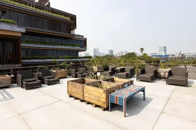 a patio with chairs and a table and a building at Orange Lodge in Bangkok