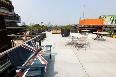 an outdoor patio with tables and chairs and benches at Orange Lodge in Bangkok