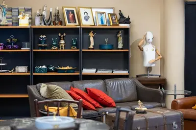 a living room with a couch and shelves of items at Orange Lodge in Bangkok
