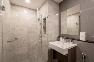 a bathroom with a white sink and a shower at 1BR Apt - Pool, Gym, Rooftop, BTS, Coworking Space - 10 min Nana Plaza - Central - New Building - 24 7 Security in Bangkok