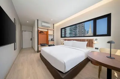 a bedroom with a bed and a desk and a large window at Asoka Hotel at Asoke Makkasan in Bangkok