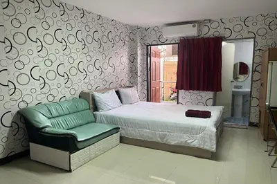 a bedroom with a bed and a green chair at Green Place 107 in Bangkok
