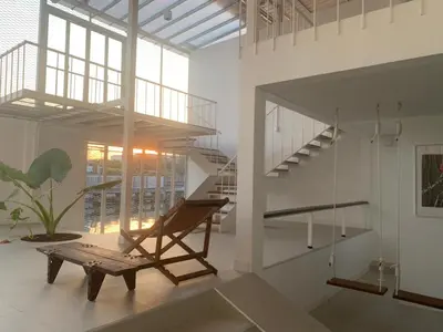 a living room with a staircase and a bench at Canal Villa on Onnut Road, near Bts Onnut, Bangkok in Amphoe Phra Khanong