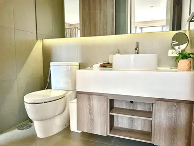 a bathroom with a white sink and a toilet at Bright & Spacious Apartment - Asoke in Bangkok