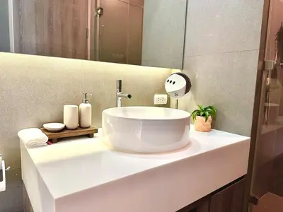 a bathroom with a white sink and a mirror at Bright & Spacious Apartment - Asoke in Bangkok
