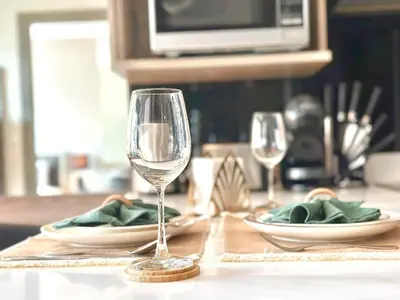 a table with two wine glasses and plates on it at Bright & Spacious Apartment - Asoke in Bangkok