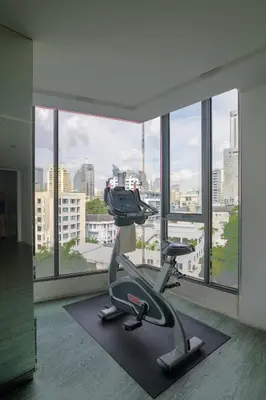 a gym with a treadmill in front of a large window at Bright & Spacious Apartment - Asoke in Bangkok