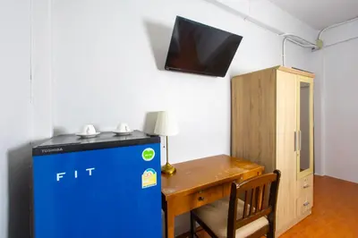 a room with a small desk and a blue refrigerator at TOM CAFE MY House in Thung Maha Mek