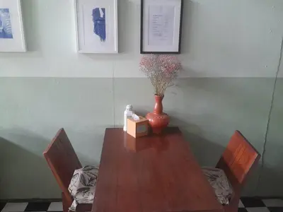 a table with a vase on it with two chairs and a vase at TOM CAFE MY House in Thung Maha Mek