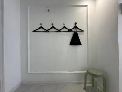 a black coat rack in a white room with a stool at Elizabeth Hotel in Bangkok