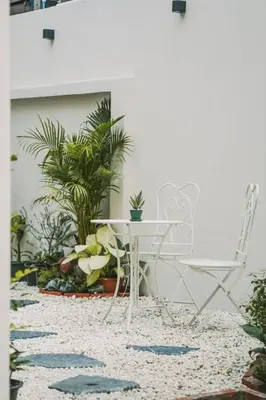 a white table and chairs on a patio with plants at Somewhere house in Bangkok