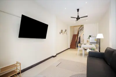 a living room with a couch and a tv on a wall at OH Homes - Samsen 10 in Bangkok