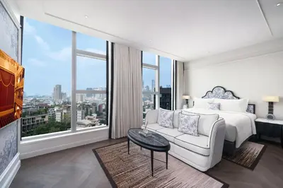 a bedroom with a bed and a couch and a large window at La Clef Bangkok by The Crest Collection in Bangkok