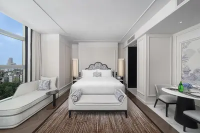 a bedroom with a bed and a couch and a table at La Clef Bangkok by The Crest Collection in Bangkok
